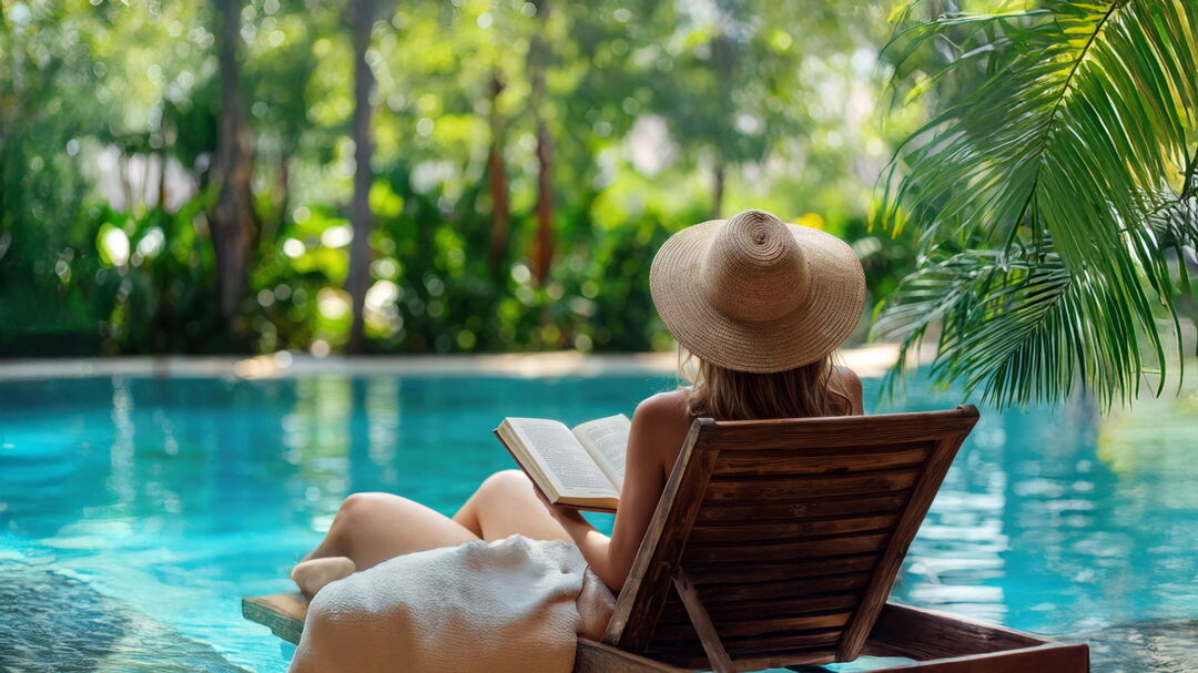 Frau am Pool mit Buch
