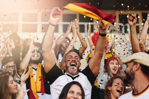 Mann mit Fanschminke jubelt im Fußballstadion